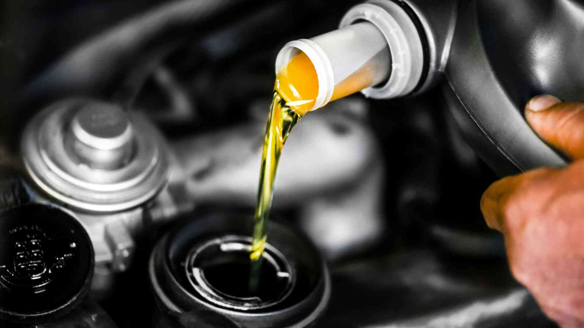 Bild på man som fyller på olja i en bil