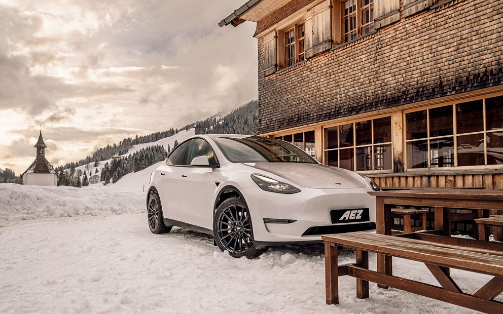Vinterlandskap på en Tesla Model 3 med svarta fälgar och vinterdäck 